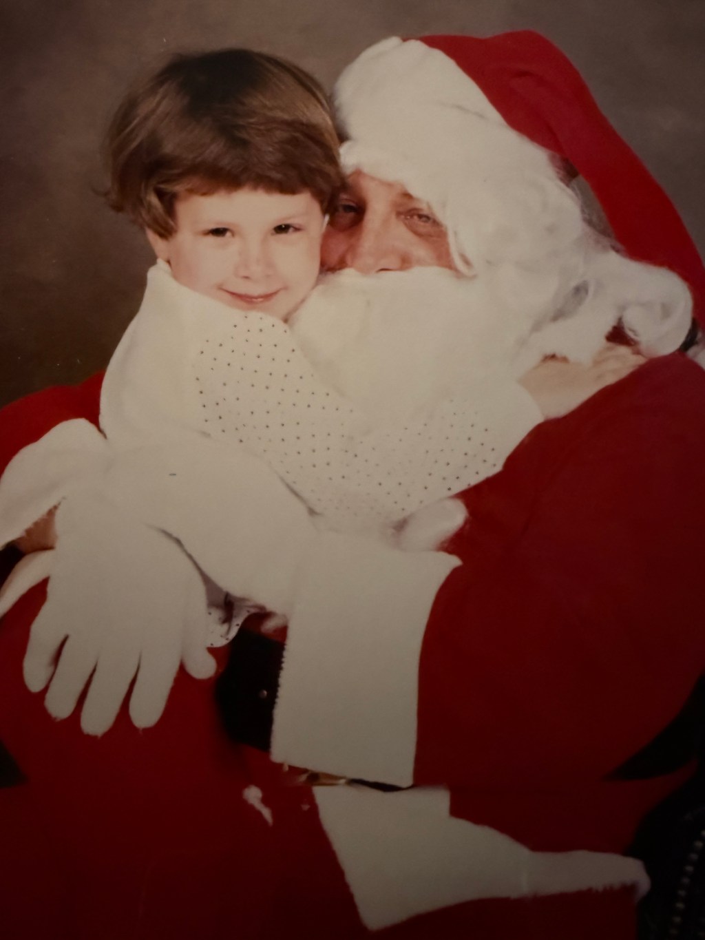 A realistic photograph of a young girl being held by Santa. Her eyes don’t smile, but her mouth does and that begs the question. Why does she know how to smile like that?
